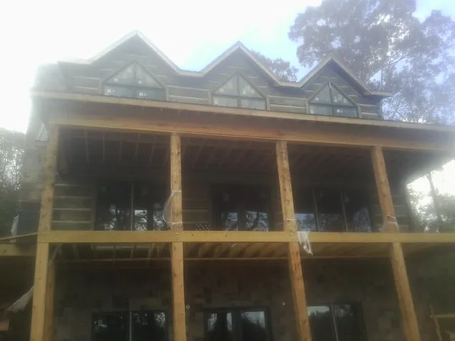 Dormers and porch framing on a large log home under construction — Roof Coating work by our crew in Raymond